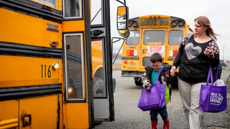 Associate Educator Jessica Clark walks with an emotional Austin Carreaux, 4, as children board...